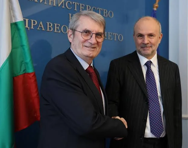 Orazio Schillaci shaking hands with Bulgarian Health Minister Hristo Hinkov in front of the Bulgarian flag and the sign of the Bulgarian Ministry of Health