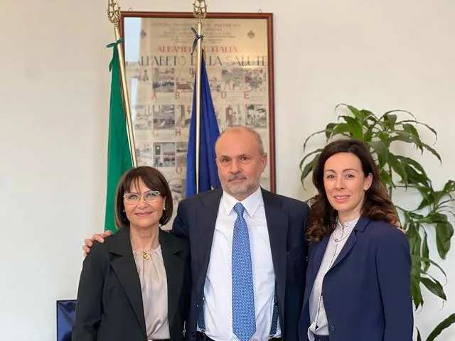 Orazio Schillaci between two women in front of a poster titled Alfabeto della Salute